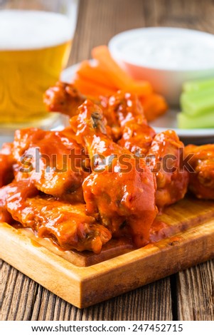 Buffalo chicken wings with cayenne pepper  sauce served hot with celery sticks and carrot sticks with blue cheese dressing for dipping and beer