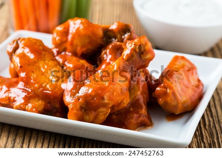 Buffalo chicken wings with cayenne pepper  sauce served hot with celery sticks and carrot sticks with blue cheese dressing for dipping