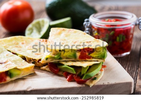 Homemade quesadilla,  corn tortilla filled with cheese,  avocado, chopped onion,  chiles, and served with red salsa