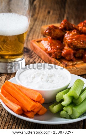 Buffalo chicken wing with cayenne pepper  sauce served hot with celery sticks and carrot sticks with blue cheese dressing for dipping and beer