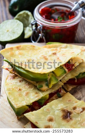 Homemade quesadilla,  corn tortilla filled with cheese,  avocado, chopped onion,  chiles, and served with red salsa