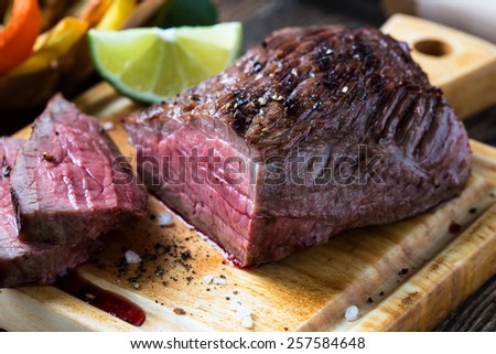 Rare roast beef sirloin with french fries on cutting board