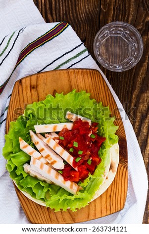 Homemade lettuce wrapped chicken fajitas served  on a flour tortilla with tomato salsa, view from above