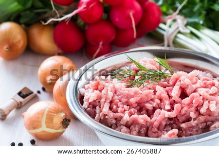 Raw ground meat in white bowl. Minced pork on a background of fresh organic vegetables