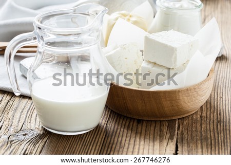 Organic dairy products on rustic wooden table. Farmer cheese in wooden bowl, milk in glass jar