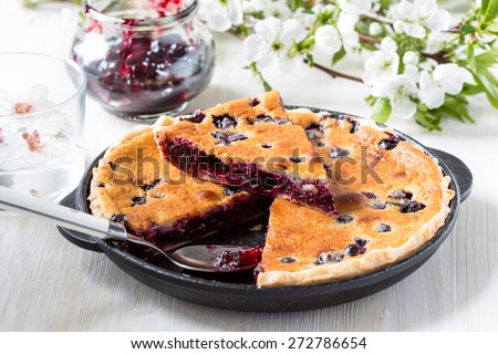 Homemade berry custard tart in frying pan on rustic background spring blossom, eco food, concept