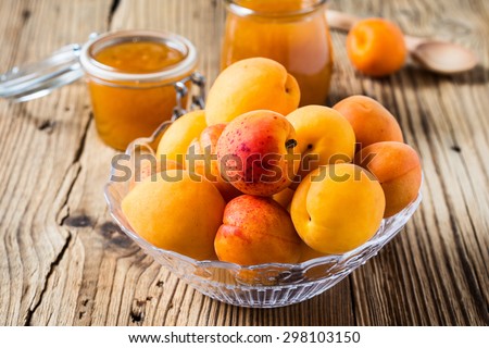 Fresh organic apricots in glass bowl and homemade apricot chutney  in a glass jar on wooden board