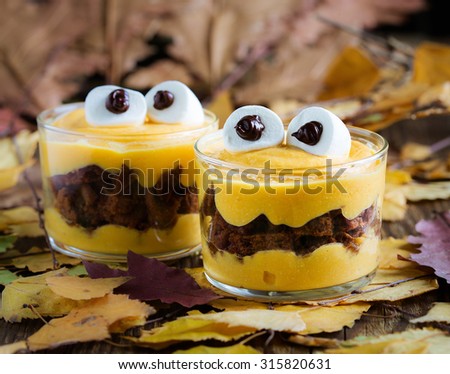 Halloween treats, little monster dessert with chocolate cookies and orange mascarpone cream  topped with big marshmallow eyes