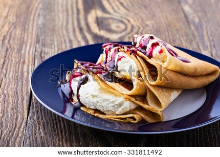 Homemade crepes with cream cheese, chocolate and berry sauce topping,