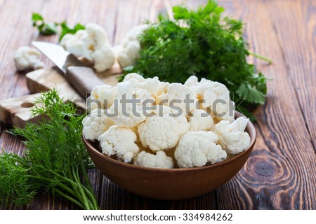 Fresh organic cauliflower cut into small pieces in ceramic bowl on wooden background