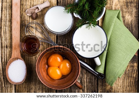 Eggnog  ingredients on rustic wooden table viewed from above.  Egg milk punch with raw egg yolks, milk, cream, sugar,  bourbon, ground nutmeg