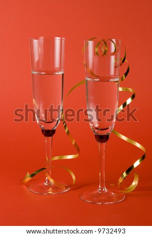 Champagne glasses with gold ribbon on red background