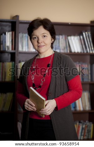 Cheerful mid-adult woman in the library. Professor, mature student, or librarian