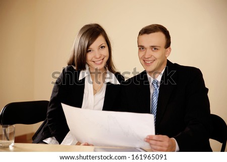Young business people woking with diagram and looking at camera in the office