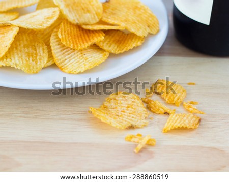 Group of potato chip on white plate and a wine bottle
