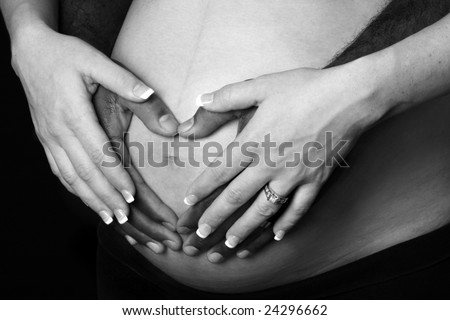 pregnant woman\'s belly with mother and fathers hands