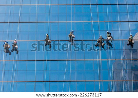 Laborers clean windows as a team on a skyscraper in downtown Seoul, South Korea