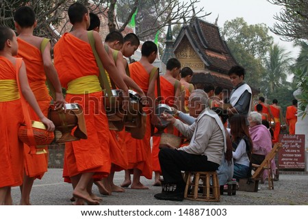 LUANG PRABANG, LAO - JANUARY 17: Every day very early in the morning, the monks walk the streets to beg give food offerings to a Buddhist monk on january 17, 2013 in Luang Prabang, Laos
