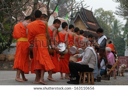 LUANG PRABANG, LAO - JANUARY 17: Every day very early in the morning, the monks walk the streets to beg give food offerings to a Buddhist monk on january 17, 2013 in Luang Prabang, Laos