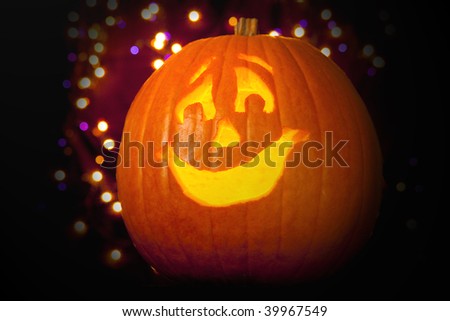 Halloween Jack-o-lantern in front of purple and orange lights.