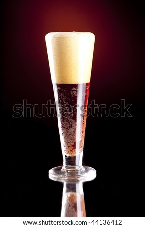 Dark Red Foaming Beer in a Pilsner Glass.