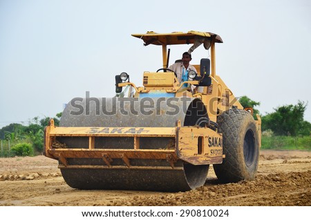 NONTHABURI, THAILAND - JUNE 12 : Road roller steamroller or vibratory roller machine and people working at construction site on June 12, 2015 in Nonthaburi, Thailand.