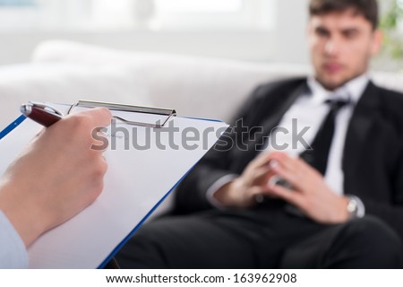 Over the shoulder view, of a business man sit on a couch talking to his psychiatrist