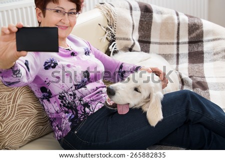 Modern senior woman with her pet shooting selfie picture by phone