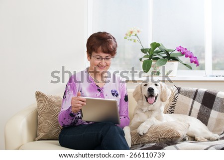 Modern senior woman with her pet looking at digital tablet