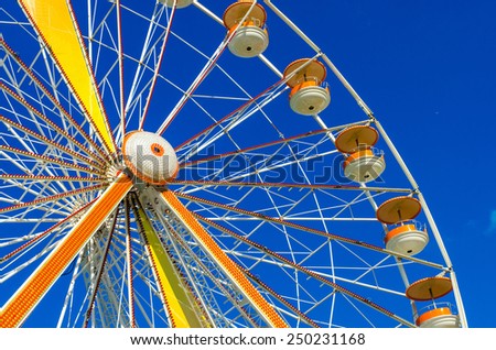 Ferris wheel with blue sky as background. Also notice airplane as small detail in the back