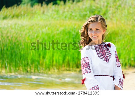Happy girl in the Ukrainian national clothes embroidery on the riverside