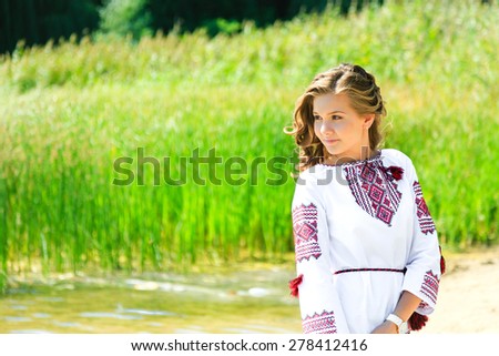 Nice girl in the Ukrainian national clothes embroidery on the riverside