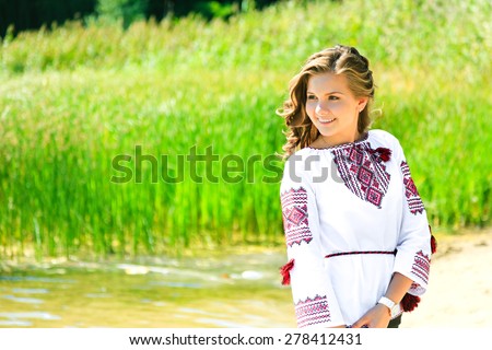 Smiling girl in the Ukrainian national clothes embroidery on the riverside