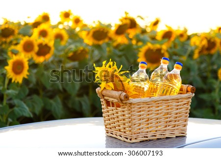 Three bottles of sunflower oil in a wicker basket on the background of the field