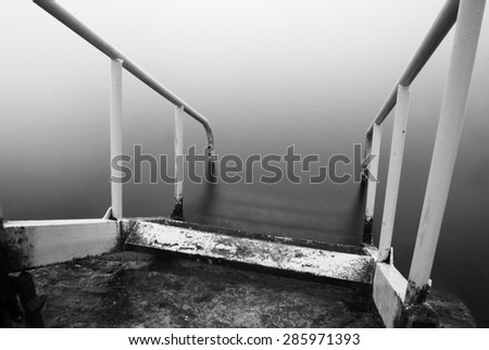 steps to nowhere. beautiful minimalist black and white seascape with stairs into the sea and milk water. shot taken in daytime \
with long exposure