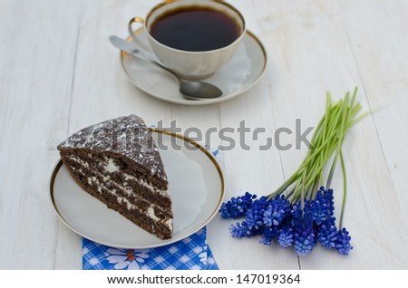 a slice of chocolate cake with a cup of coffee and bird cherry