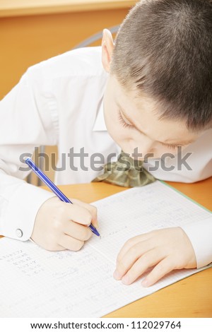 Boy in white shirt writing at desk above view