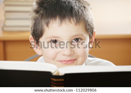 Smiling boy looking over open book with black cover closeup photo