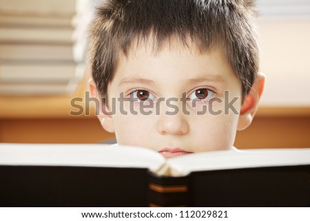 Boy looking over open book with black cover closeup photo