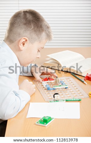 Boy at desk assembling electrical circuit