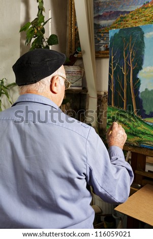 Artist at work painting picture in workshop rear view