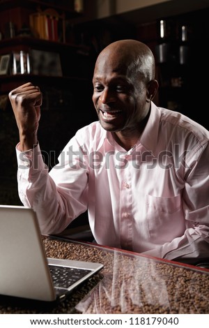 Satisfied african man in pink shirt gesturing and shouting at laptop
