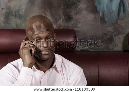 Surprized african man in pink shirt talking on mobile phone
