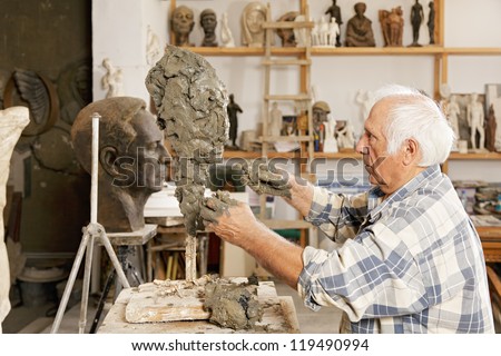 Senior sculptor making sculpture putting clay on wire skeleton sideview