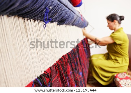 Loom for hand weaving carpet with woman working at backstage