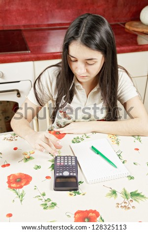 Serious woman making calculations at table in the kitchen