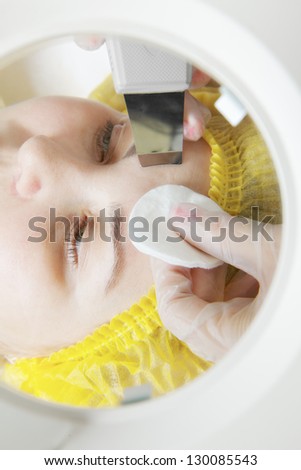 Beautician hands at face cleaning procedure view through magnifier