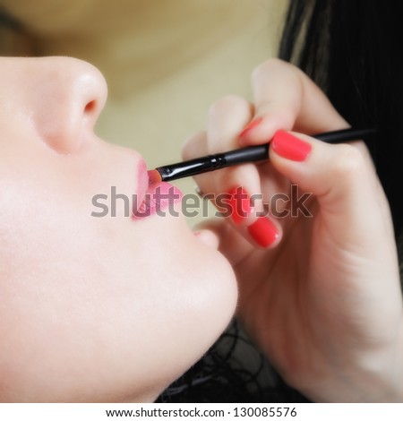 Cosmetician applying lipstick sideview closeup