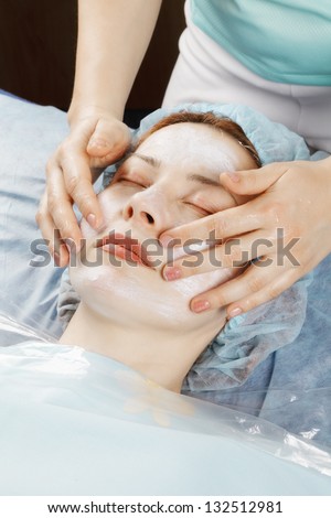 Redhead woman laying down on couch having face massage