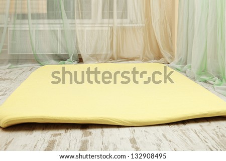 Yellow foam rubber mat on the wooden floor of gym